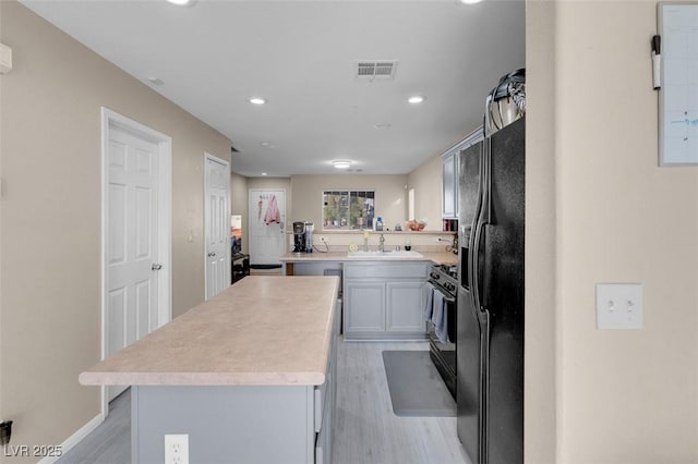 kitchen with black appliances, a center island, light hardwood / wood-style floors, sink, and kitchen peninsula