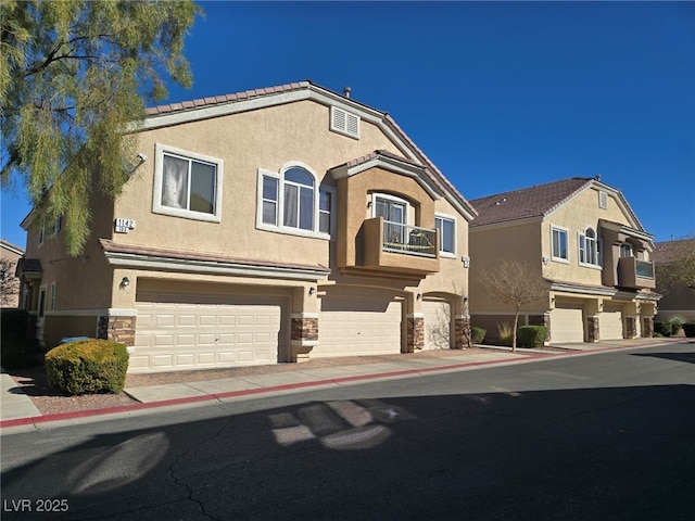 view of front facade with a garage, stone siding, a balcony, and stucco siding