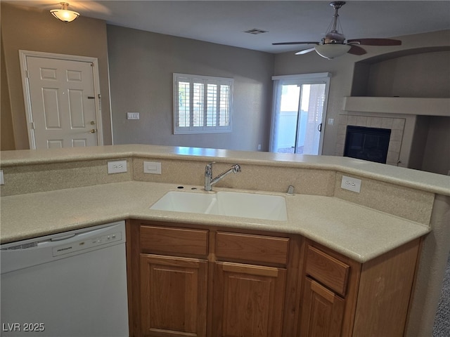 kitchen featuring visible vents, brown cabinetry, dishwasher, light countertops, and a sink