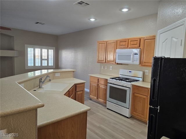 kitchen featuring white appliances, visible vents, light countertops, and a sink