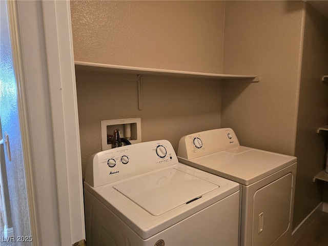 laundry area with washing machine and dryer and a textured wall