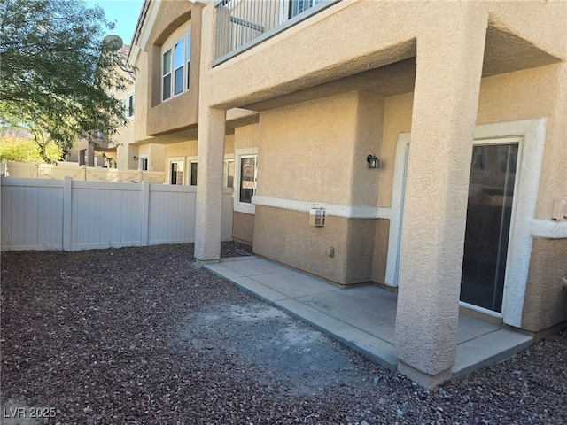 exterior space with a patio area, fence, and stucco siding