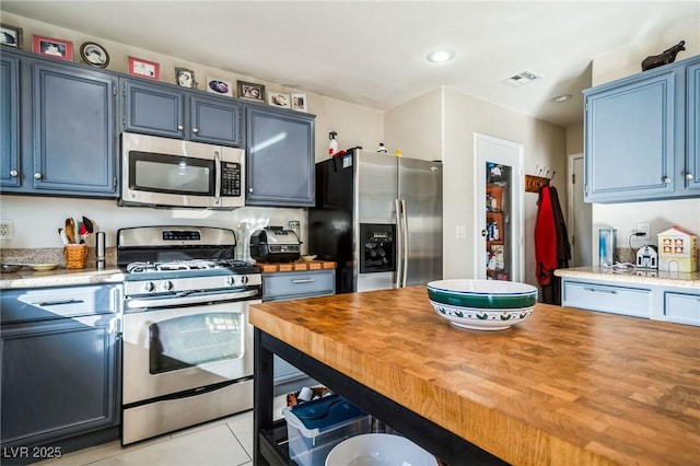 kitchen with light tile patterned flooring, stainless steel appliances, and blue cabinets