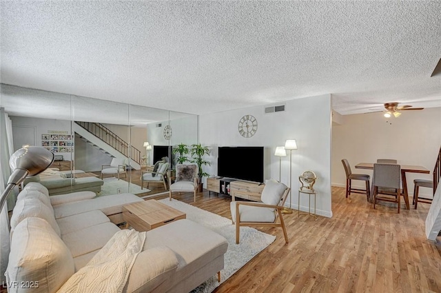 living room featuring ceiling fan, a textured ceiling, and hardwood / wood-style floors