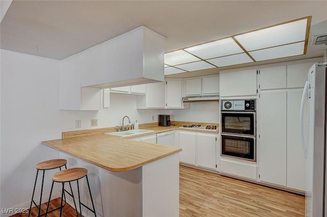 kitchen featuring a breakfast bar, kitchen peninsula, sink, white appliances, and white cabinetry