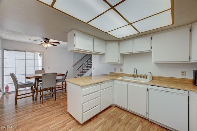 kitchen with dishwasher, light hardwood / wood-style floors, kitchen peninsula, sink, and white cabinets