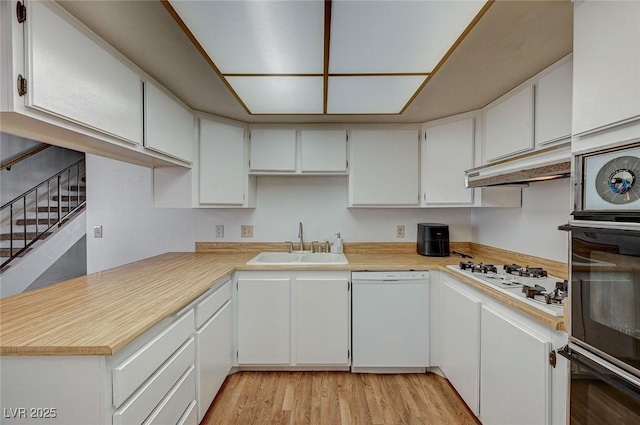 kitchen featuring sink, white appliances, white cabinets, and light hardwood / wood-style flooring