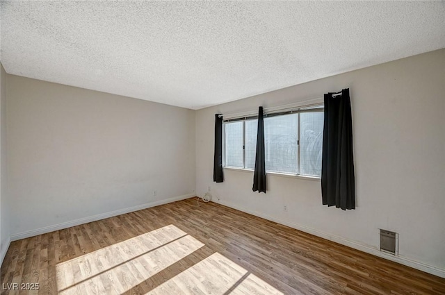 unfurnished room featuring wood-type flooring and a textured ceiling