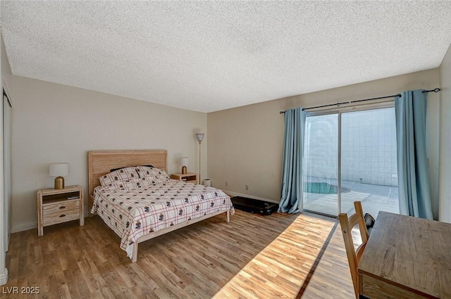 bedroom featuring a textured ceiling, access to exterior, and hardwood / wood-style floors