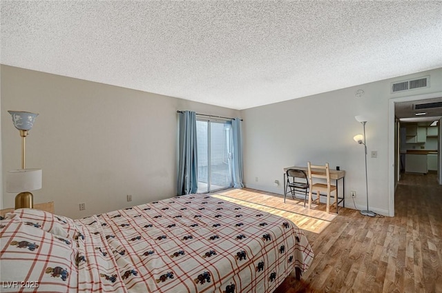 bedroom with a textured ceiling, access to exterior, and wood-type flooring