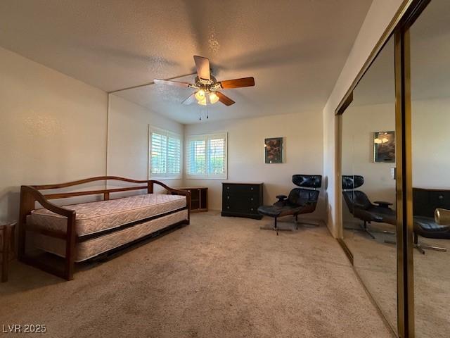 carpeted bedroom featuring ceiling fan, a closet, and a textured ceiling