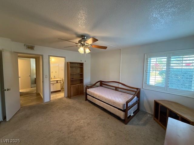 carpeted bedroom featuring a textured ceiling, ceiling fan, and connected bathroom