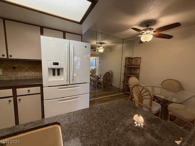 kitchen featuring ceiling fan, white cabinetry, decorative backsplash, and white fridge with ice dispenser