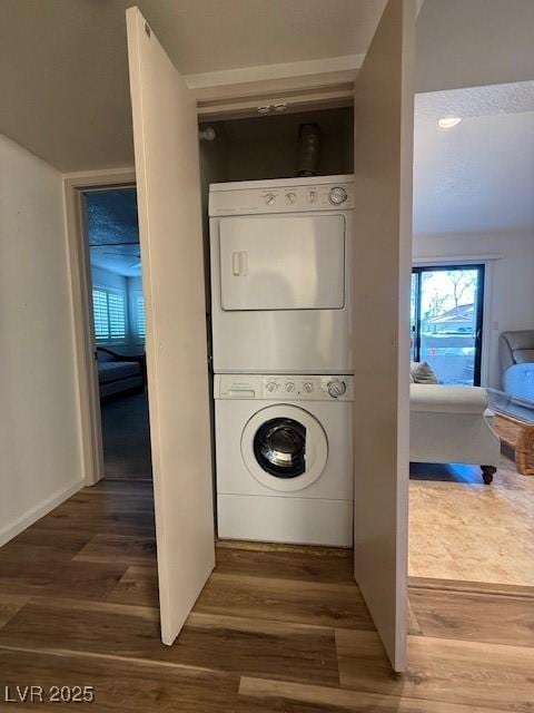 washroom with hardwood / wood-style floors and stacked washer and dryer