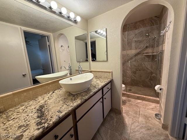 bathroom with an enclosed shower, vanity, toilet, and a textured ceiling