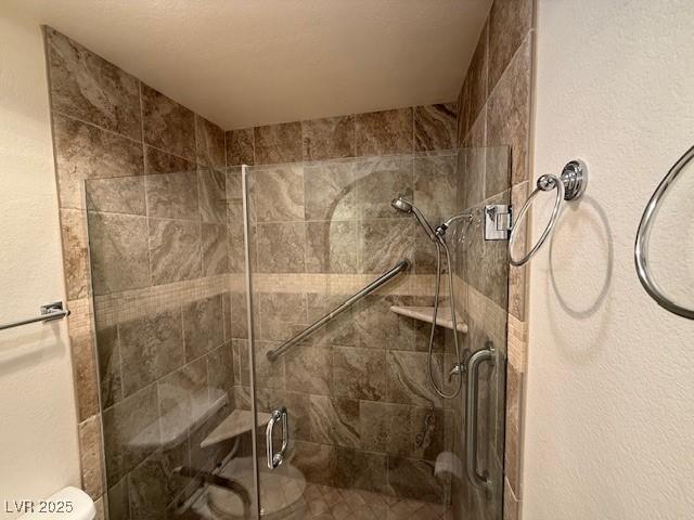 bathroom featuring toilet and a shower with shower door