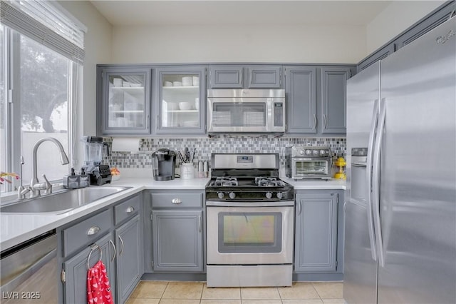 kitchen with stainless steel appliances, light tile patterned flooring, sink, and gray cabinets