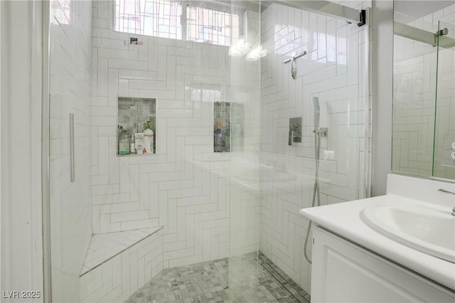 bathroom featuring a shower with door and vanity