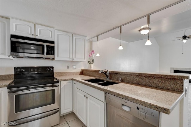 kitchen featuring kitchen peninsula, appliances with stainless steel finishes, pendant lighting, white cabinets, and sink