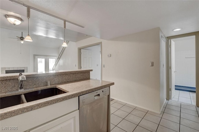 kitchen featuring white cabinetry, ceiling fan, stainless steel dishwasher, a tile fireplace, and sink