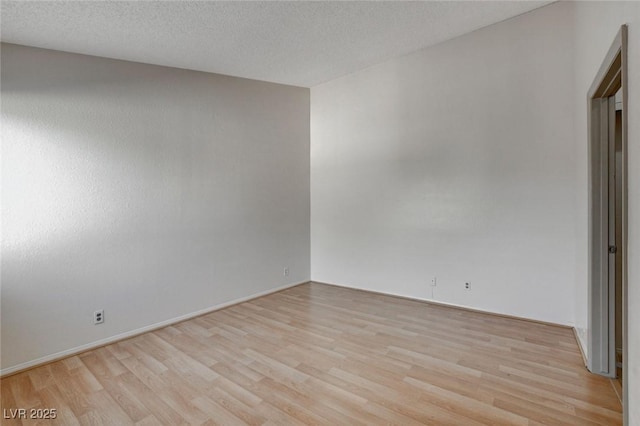 spare room featuring light wood-type flooring and a textured ceiling