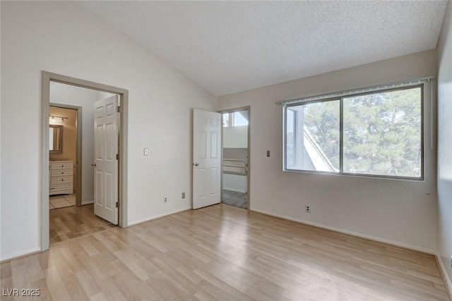 unfurnished bedroom with vaulted ceiling, a textured ceiling, and light hardwood / wood-style flooring