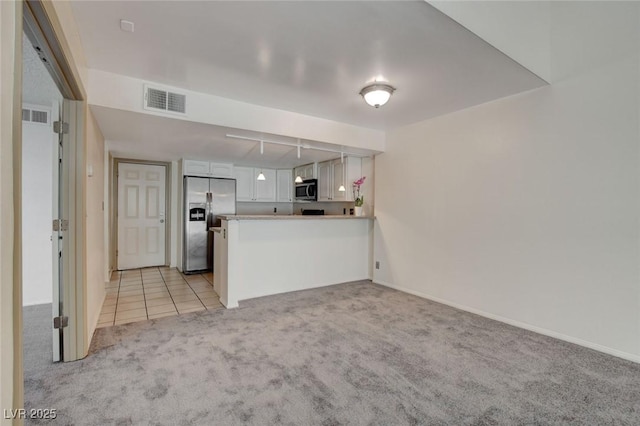 kitchen with appliances with stainless steel finishes, white cabinetry, light carpet, and kitchen peninsula