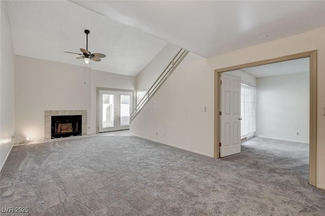 unfurnished living room featuring ceiling fan, lofted ceiling, light colored carpet, french doors, and a tile fireplace