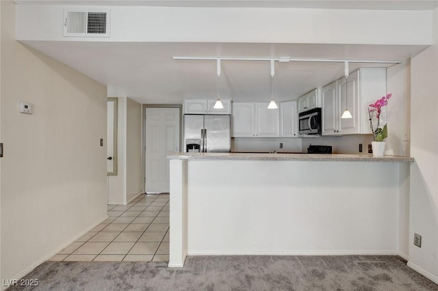 kitchen featuring light tile patterned floors, kitchen peninsula, appliances with stainless steel finishes, and white cabinetry