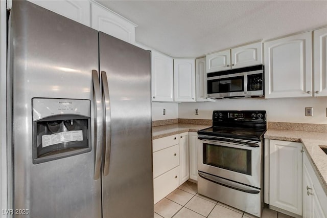 kitchen with light tile patterned flooring, appliances with stainless steel finishes, a textured ceiling, and white cabinetry