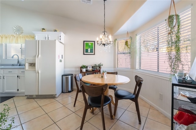 tiled dining area featuring sink, plenty of natural light, a notable chandelier, and vaulted ceiling