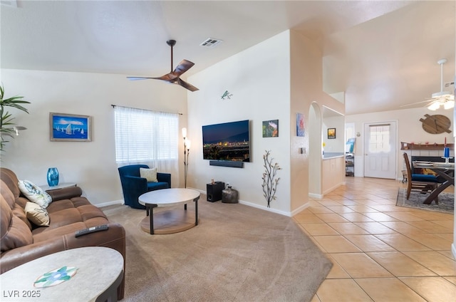 tiled living room with ceiling fan and high vaulted ceiling