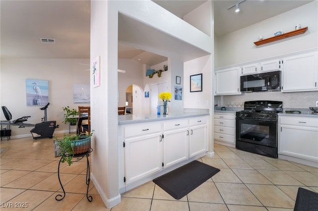 kitchen featuring black appliances, white cabinets, light tile patterned floors, and lofted ceiling