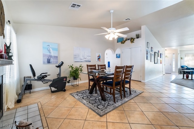 tiled dining room with ceiling fan, lofted ceiling, and a tiled fireplace