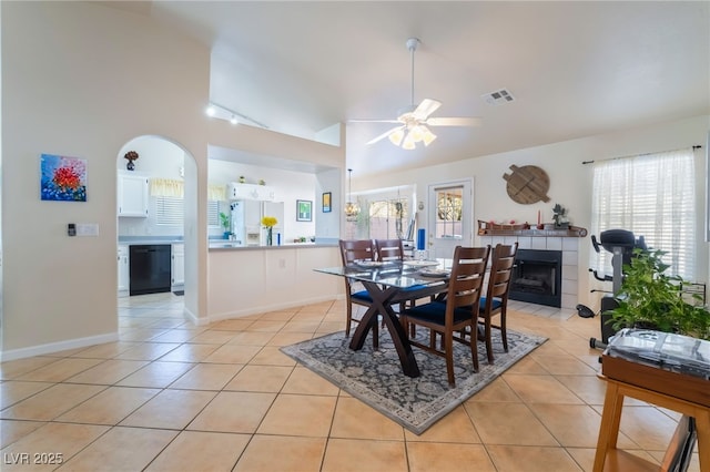 tiled dining area with ceiling fan and a tile fireplace