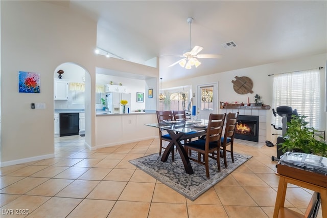 tiled dining room featuring ceiling fan, lofted ceiling, and a fireplace