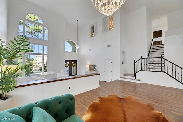 living room featuring wood-type flooring, a notable chandelier, and a high ceiling