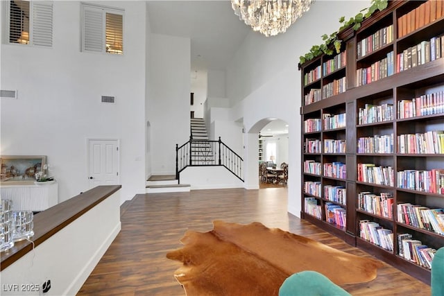 interior space with wood-type flooring, a towering ceiling, and an inviting chandelier