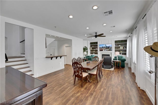 dining space featuring ceiling fan, built in shelves, and dark hardwood / wood-style floors