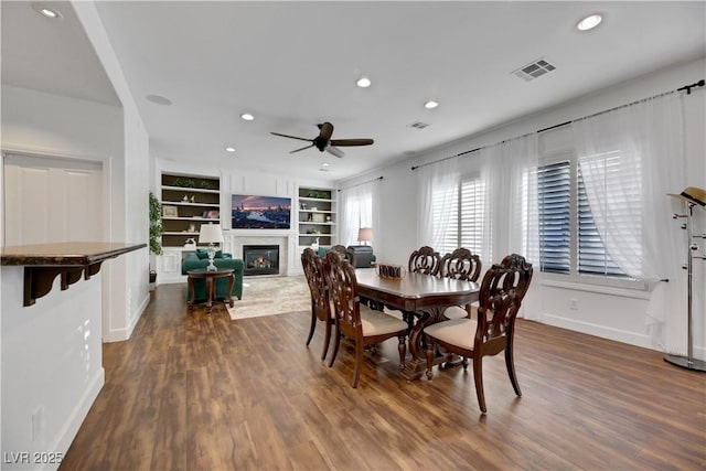 dining room with ceiling fan, dark hardwood / wood-style flooring, and built in shelves