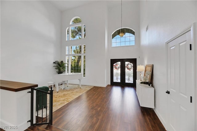 foyer entrance with french doors, dark wood-type flooring, plenty of natural light, and a high ceiling