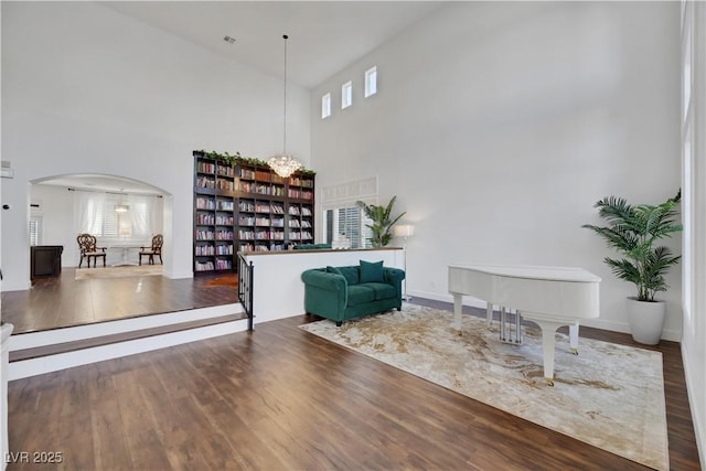 sitting room with hardwood / wood-style floors and a towering ceiling