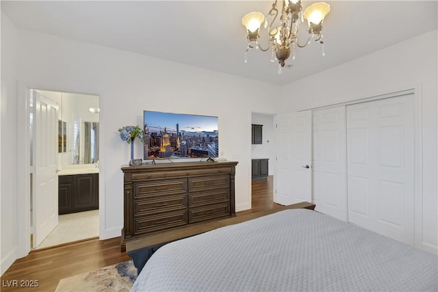 bedroom with light wood-type flooring, a closet, connected bathroom, and an inviting chandelier