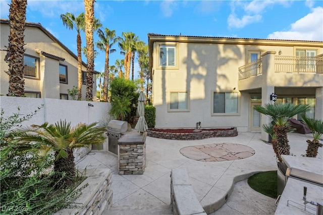 rear view of house featuring a balcony, an outdoor kitchen, and a patio