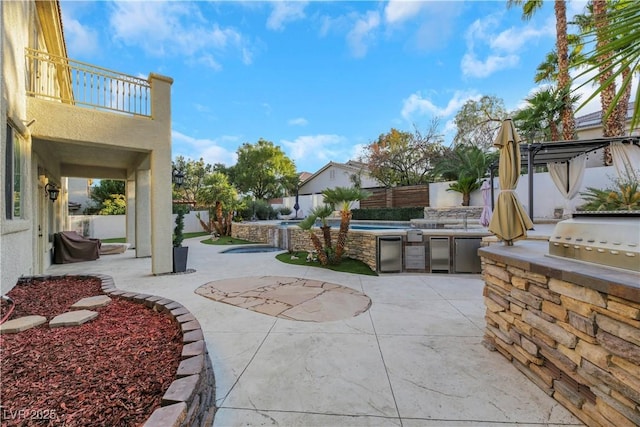 view of patio with a balcony, area for grilling, and exterior kitchen