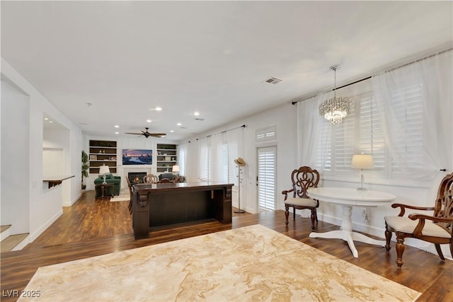 kitchen with ceiling fan with notable chandelier, built in shelves, dark hardwood / wood-style floors, and hanging light fixtures