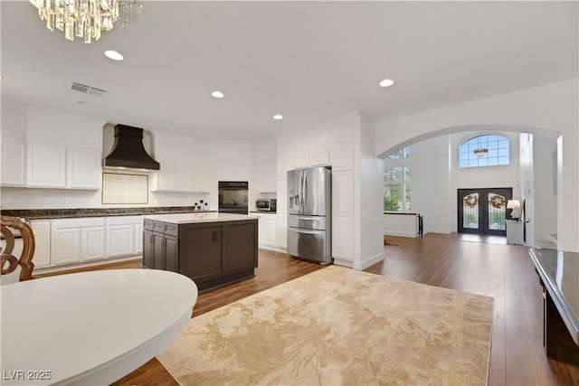 kitchen featuring a center island, custom exhaust hood, stainless steel appliances, white cabinets, and french doors