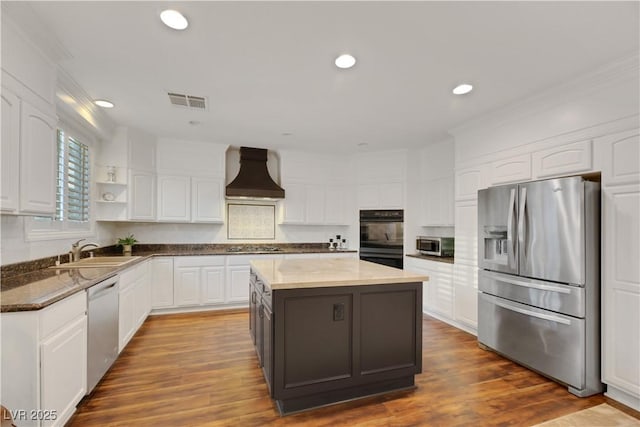 kitchen featuring custom exhaust hood, white cabinets, stainless steel appliances, and a center island