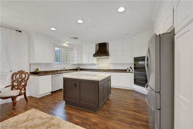 kitchen with custom exhaust hood, a center island, white cabinets, and stainless steel refrigerator