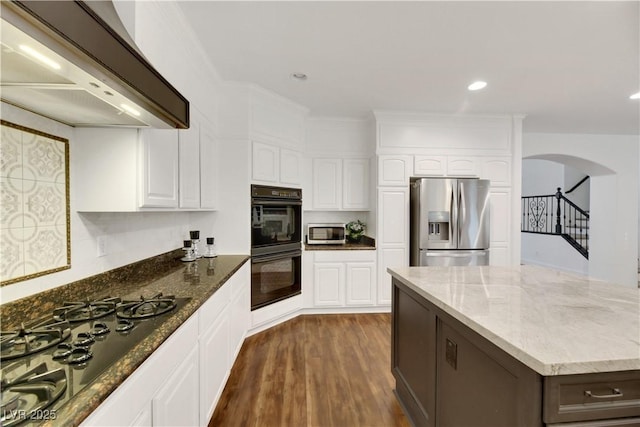 kitchen with light stone countertops, premium range hood, white cabinets, and black appliances